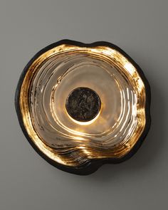 a gold and black bowl with a coin in the center on a gray surface,