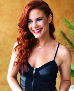 a woman with red hair wearing a black top