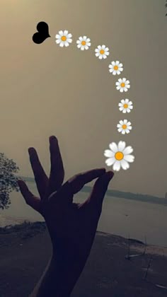 someone holding their hand up in the air with daisies on it and two hearts above them