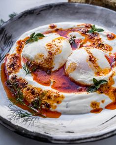 two mozzarellas with sauce and herbs on a plate