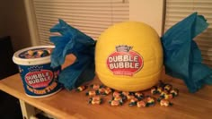 a large yellow bubble gummy ball sitting on top of a table next to a bucket of bubble gums