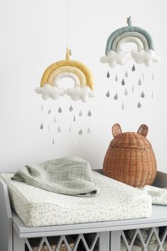 a baby's crib with an umbrella and clouds hanging from the ceiling