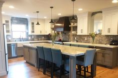 a large kitchen with an island in the middle and lots of chairs at the counter