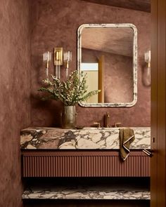 a bathroom with marble counter tops and gold fixtures on the wall, along with a large mirror