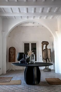 a table with vases and other items on it in a room that has white walls