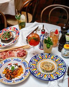 a table topped with plates and glasses filled with food on top of a white table cloth