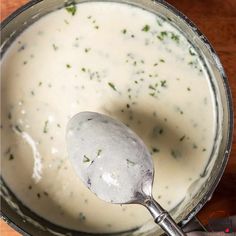 a ladle filled with cream sauce on top of a wooden table