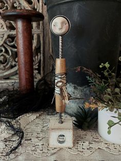 a small wooden sculpture sitting on top of a table next to a potted plant