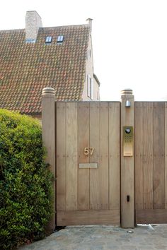 a wooden gate with numbers on it in front of a house