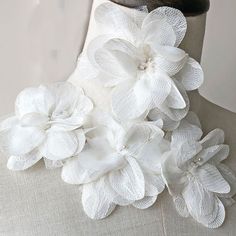 a mannequin with white flowers on it's neck and an object in the background