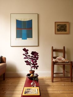 a living room with a red coffee table and two chairs in front of a painting on the wall