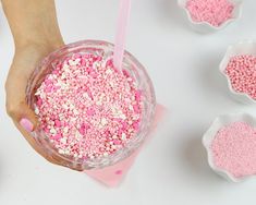 pink sprinkles in a cup being held by a woman's hand