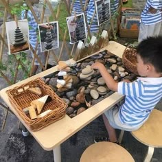 a boy sitting at a table playing with rocks