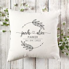 a personalized pillow with the name and date on it, sitting next to some flowers