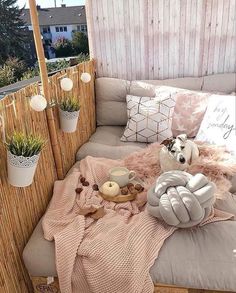 a dog sitting on top of a couch covered in blankets and pillows next to potted plants