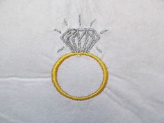 a diamond ring is on top of a white sheet with yellow thread and silver beads