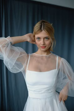 a woman in a white dress posing with her hands on her head