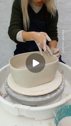 a woman is making a bowl out of clay