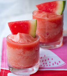 a glass filled with ice and watermelon slices next to a pink striped straw