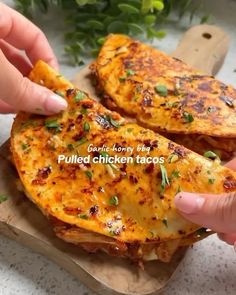 two pieces of bread with cheese and herbs on it being held by someone's hand