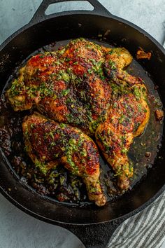 a close up of a chicken in a skillet on a table with utensils