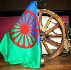 an old wooden wagon wheel with a flag on it's side next to other items