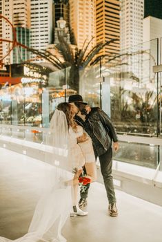 a bride and groom kissing in front of the las vegas city skyline at their wedding