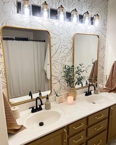 a bathroom with two sinks, mirrors and lights on the wall above them is shown