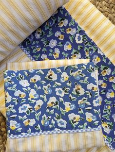 three pieces of blue and yellow fabric with flowers on them are folded neatly in the same pattern