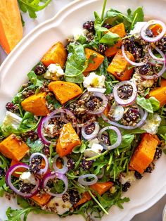 a white plate topped with salad next to sliced carrots