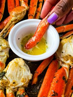 a person dipping some food into a small white bowl with carrots and crab legs