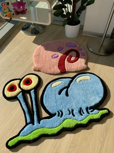 two rugs on the floor with an image of a blue snail and a pink one