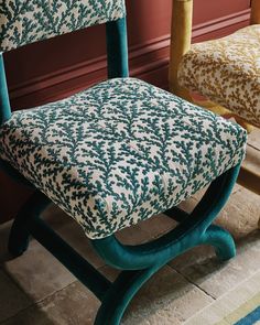 a chair that has been upholstered with blue and white fabric, sitting in front of a red wall