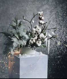 a vase filled with white flowers and greenery on top of a block of ice