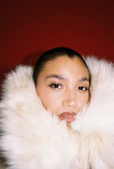 a woman wearing a white fur coat and posing for the camera with her eyes closed