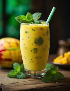 a glass filled with fruit and mint sitting on top of a wooden table next to other fruits