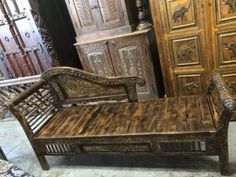 an old wooden bench sitting in front of some antique doors and other furniture on display