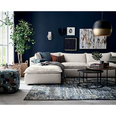 an image of a living room setting with dark blue walls and white couches in the middle