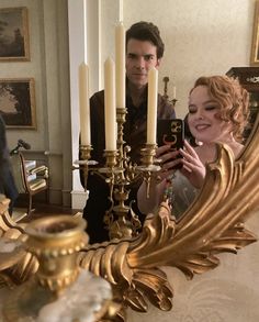 a woman taking a selfie in front of a gold candelabra with candles