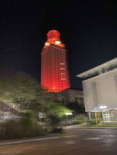 a tall building with a red light on it's top and trees in the foreground