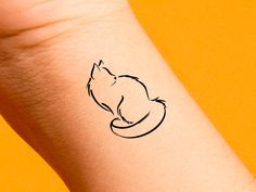 a small black cat tattoo on the left inner arm and wrist, with an orange background