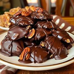 a plate full of chocolate covered pecans on a table with other desserts in the background