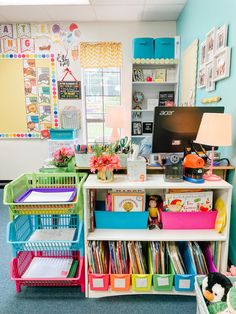 a room filled with lots of different colored bins next to a computer desk and bookshelf