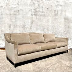 a tan couch sitting in front of a white wall with no one on it's legs