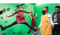 children wearing face masks while standing in front of climbing wall