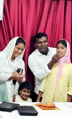 a family poses for a photo in front of a cake