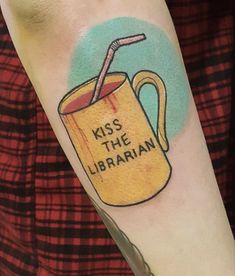 a person with a tattoo on their arm has a drink in the mug that says kiss the librarian