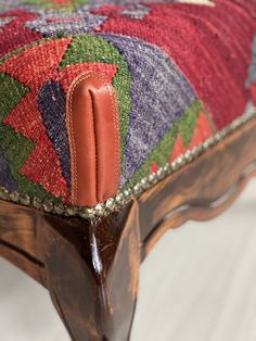 an upholstered footstool with colorful fabric and leather on it's sides