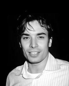 a black and white photo of a young man in a shirt smiling at the camera