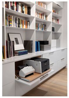 a printer on a desk in front of bookshelves